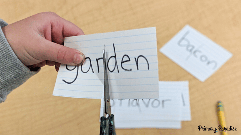 a student cutting the word garden into the syllables gar and den