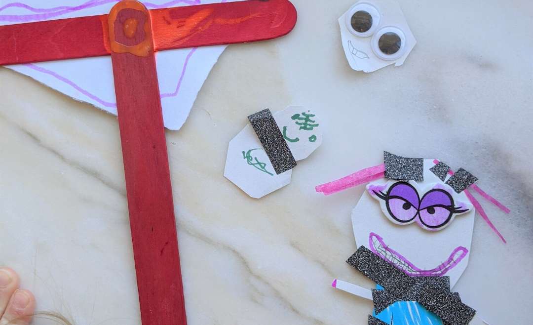 little people and object made by a child from scrap paper, popsicle sticks, and googly eyes